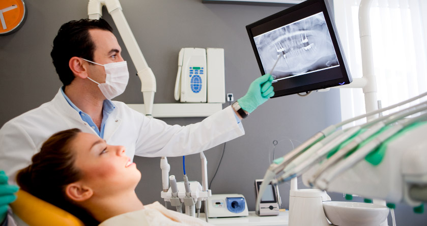 dentist and patient lookng at dental x-ray for tooth extraction