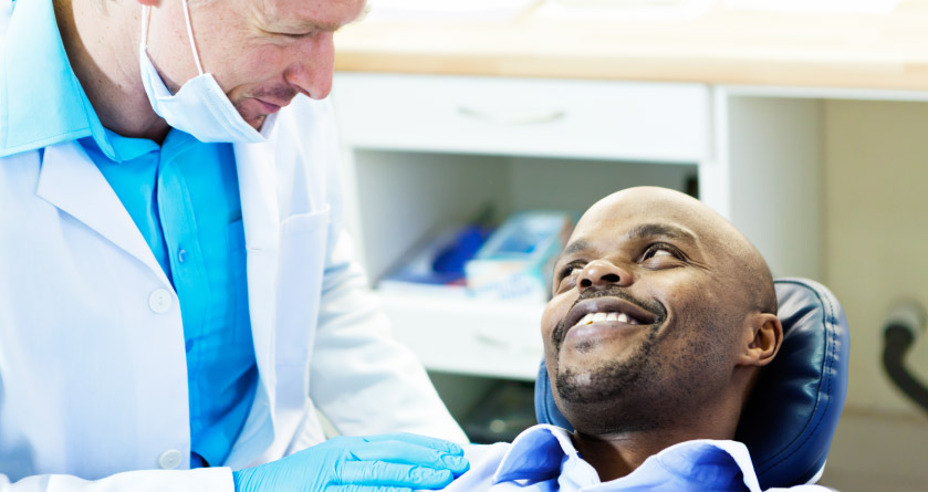 A male patient smiling at dentist after his root canal treatment