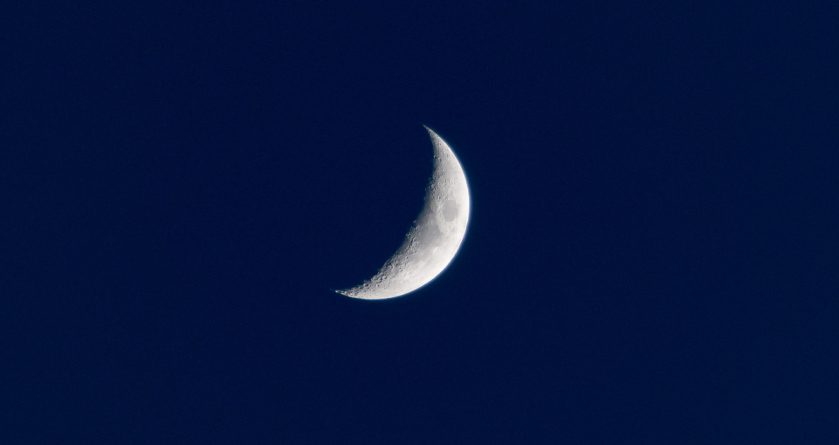 White crescent moon against a navy sky during the night, when most people sleep