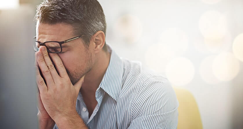 bearded man holding the top of his head with a headache