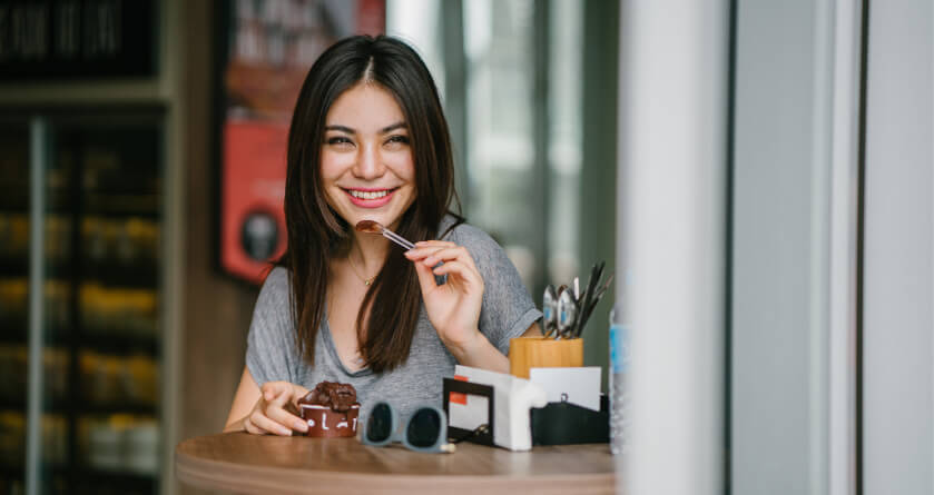 dark haired girl eating chocolate ice cream out of a cup at a cafe