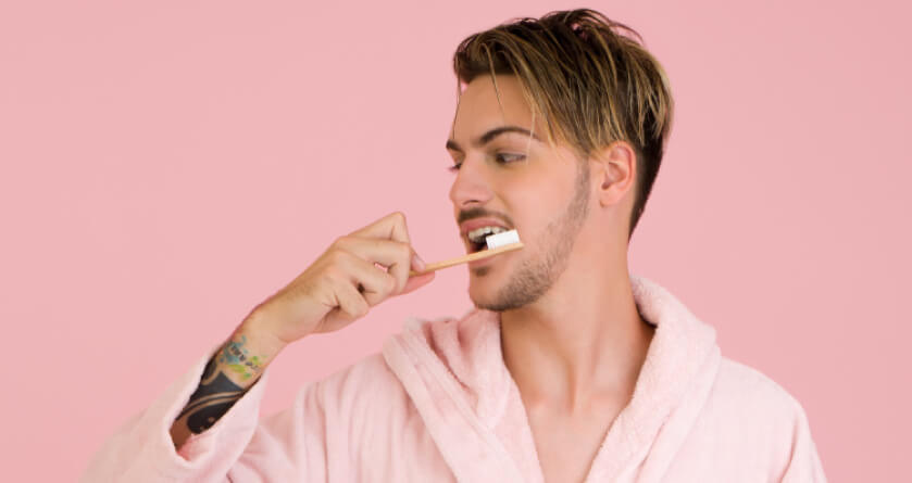 man in his robe brushing his teeth