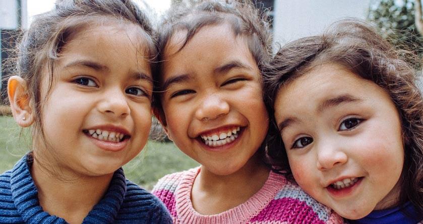 three young girls with big toothy smiles 