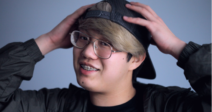young blond boy wearing glasses, a hat and braces on his teeth