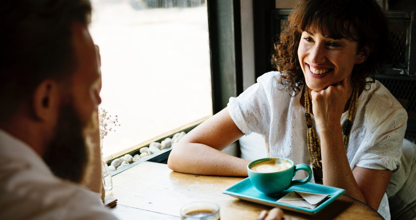 woman smiling having coffee with a bearded man