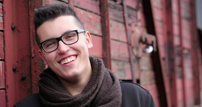 young man with glasses and a scarf smiling 