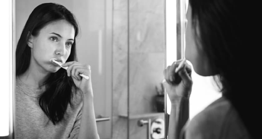 girl looking in the mirror brushing her teeth