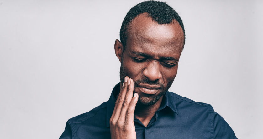 man holding his jaw with TMJ pain