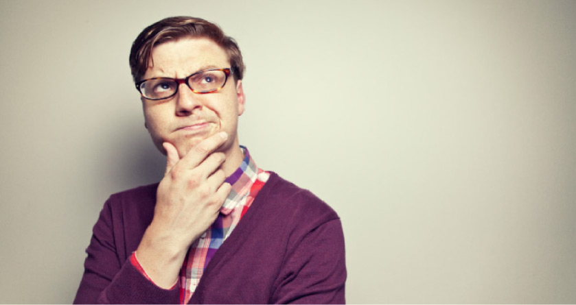 man wearing glasses and a purple sweater holds his chin pondering wisdom teeth removal