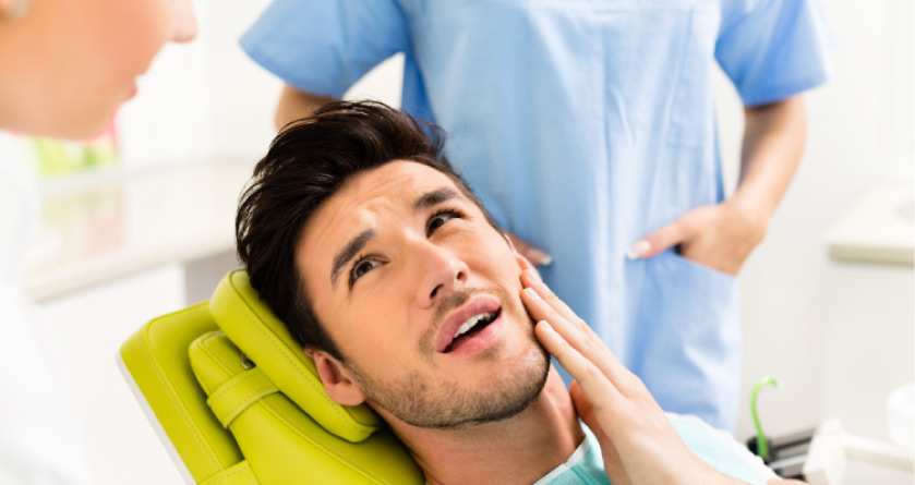 man holding his jaw in the dentist's chair ready for oral surgery