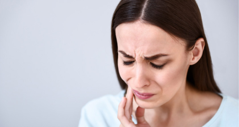 woman holding her jaw in pain from a tmj disorder