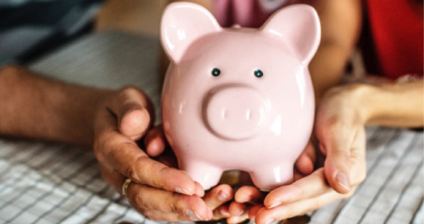 large and small hands holding a pink piggy bank