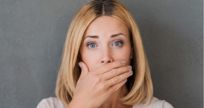 woman covers her mouth with her hand to hide gum disease