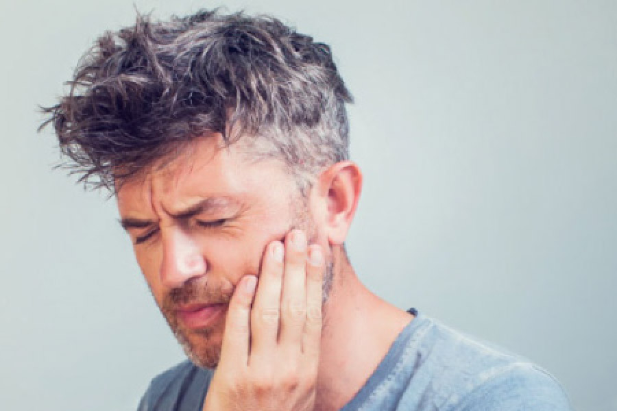 man holding his jaw in pain