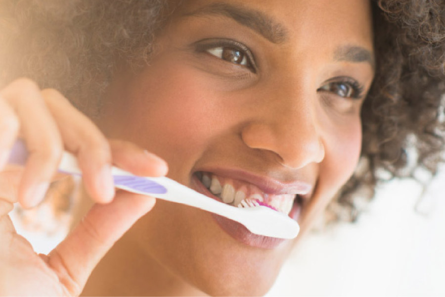 young woman brushes her teeth to ward off tooth decay