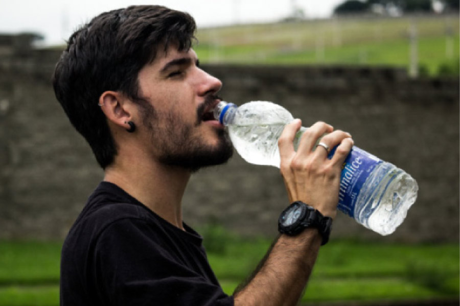 man drinking from a water bottle to stay hydrated