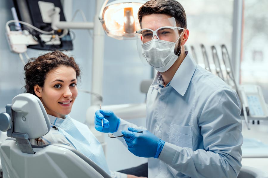 young patient sits in the dental chair as the dentist prepares for oral surgery while wearing a mask