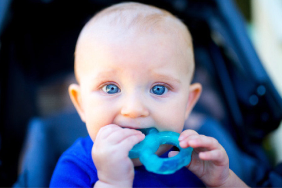 blue eyed baby chewing on a blue teething toy