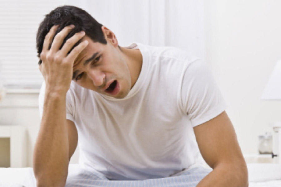 man holds his head and yawns after a sleepless night