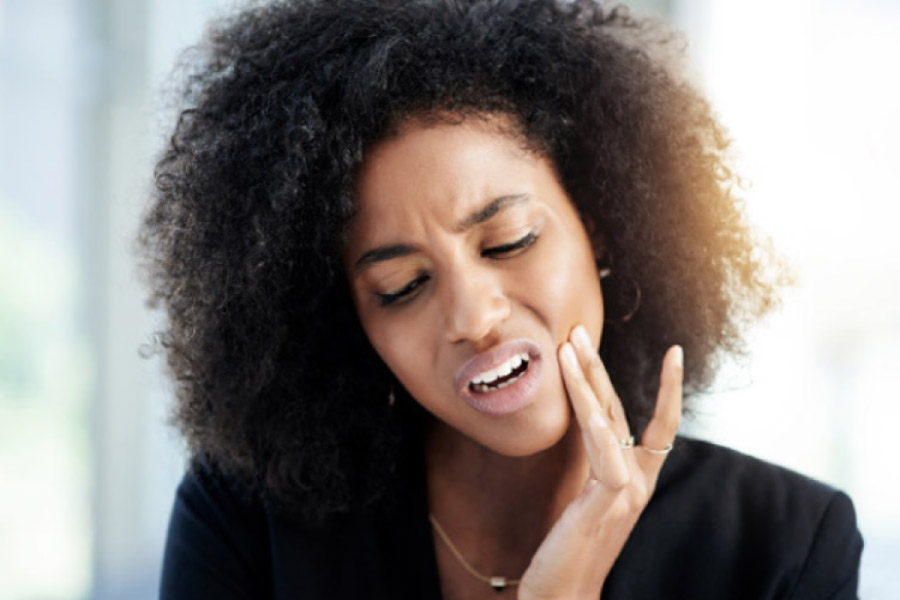 dark haired woman holding her jaw in pain with a dental emergency