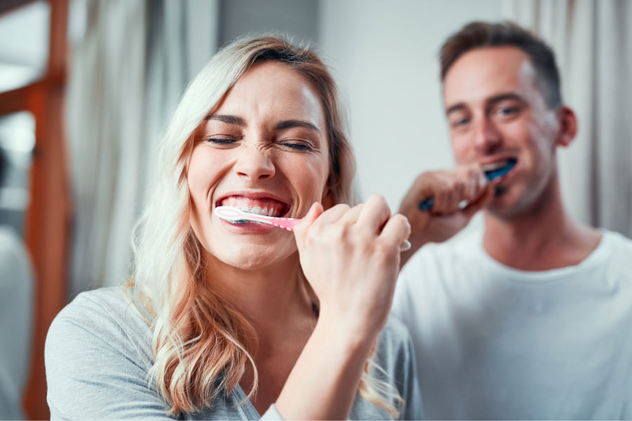 couple brushing their teeth with a fluoride toothpaste