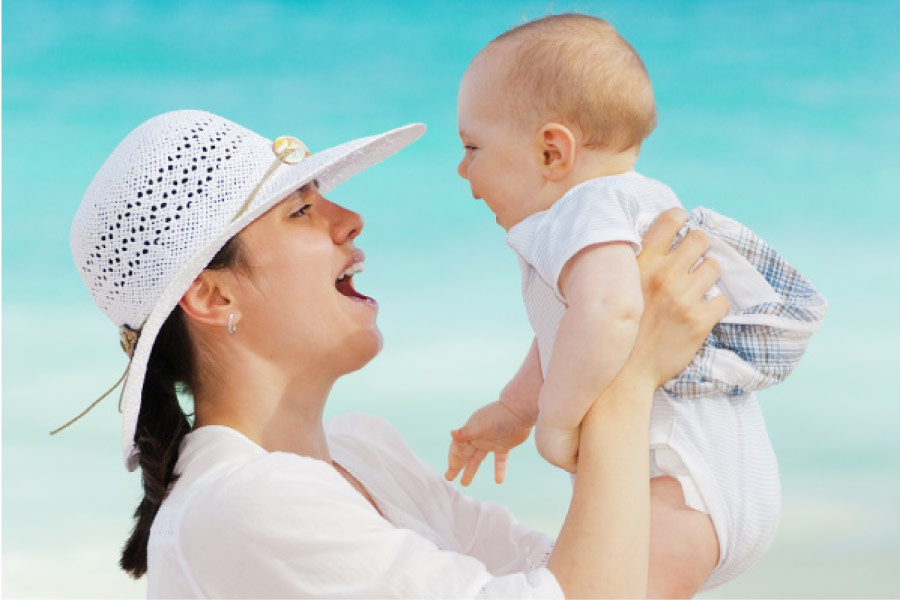 mother wearing a bonnet holds up her baby with both hands