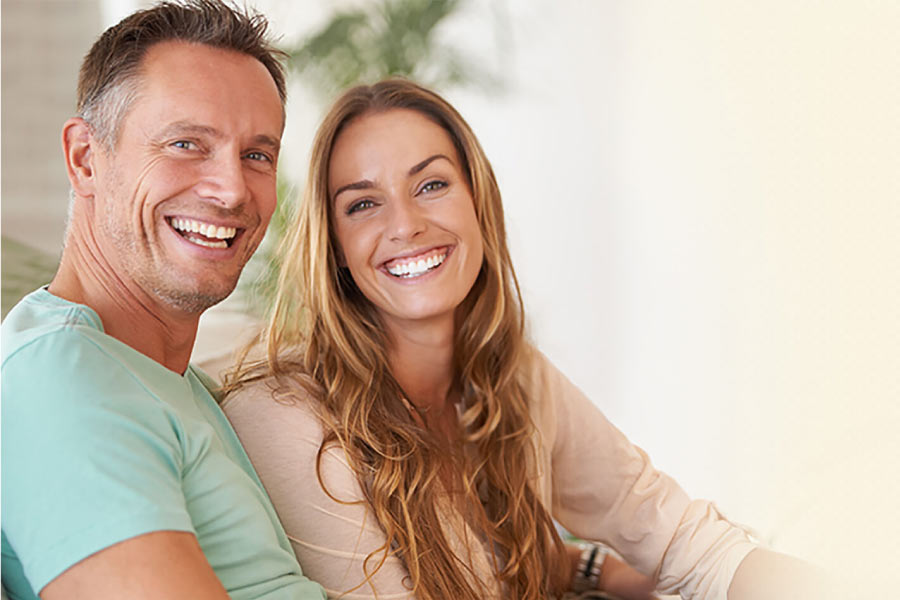 couple smile after getting dental implants to replace missing teeth