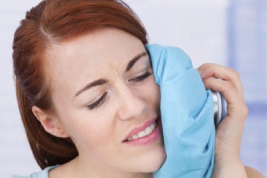 woman holds and icepack to her jaw after oral surgery