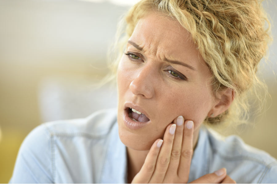 woman holds her jaw in pain with a TMJ disorder