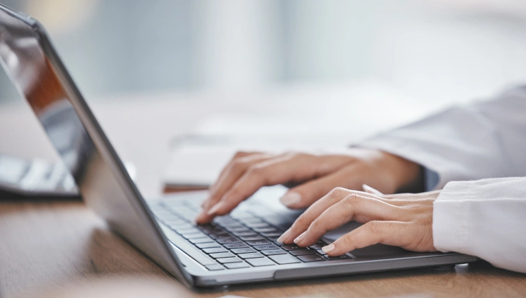 Person typing on laptop at desk in professional office setting